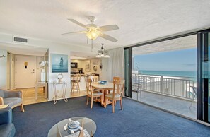 A hotel room with a balcony, a dining area, and a view of the beach. - House Of The Sun #414GF (Sarasota)