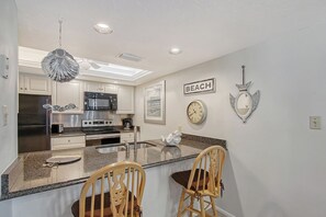 A kitchen with a central island, stainless steel appliances, and a clock on the wall.
