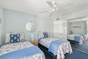 A hotel room with two beds, a ceiling fan, a mirror, and a clock on the wall. - House Of The Sun #414GF (Sarasota)