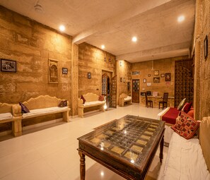 A room with a large wooden table, two sofas, and a patterned wall. - Exotic Luxury Desert Camp- The Art of Desert Living (Jaisalmer)