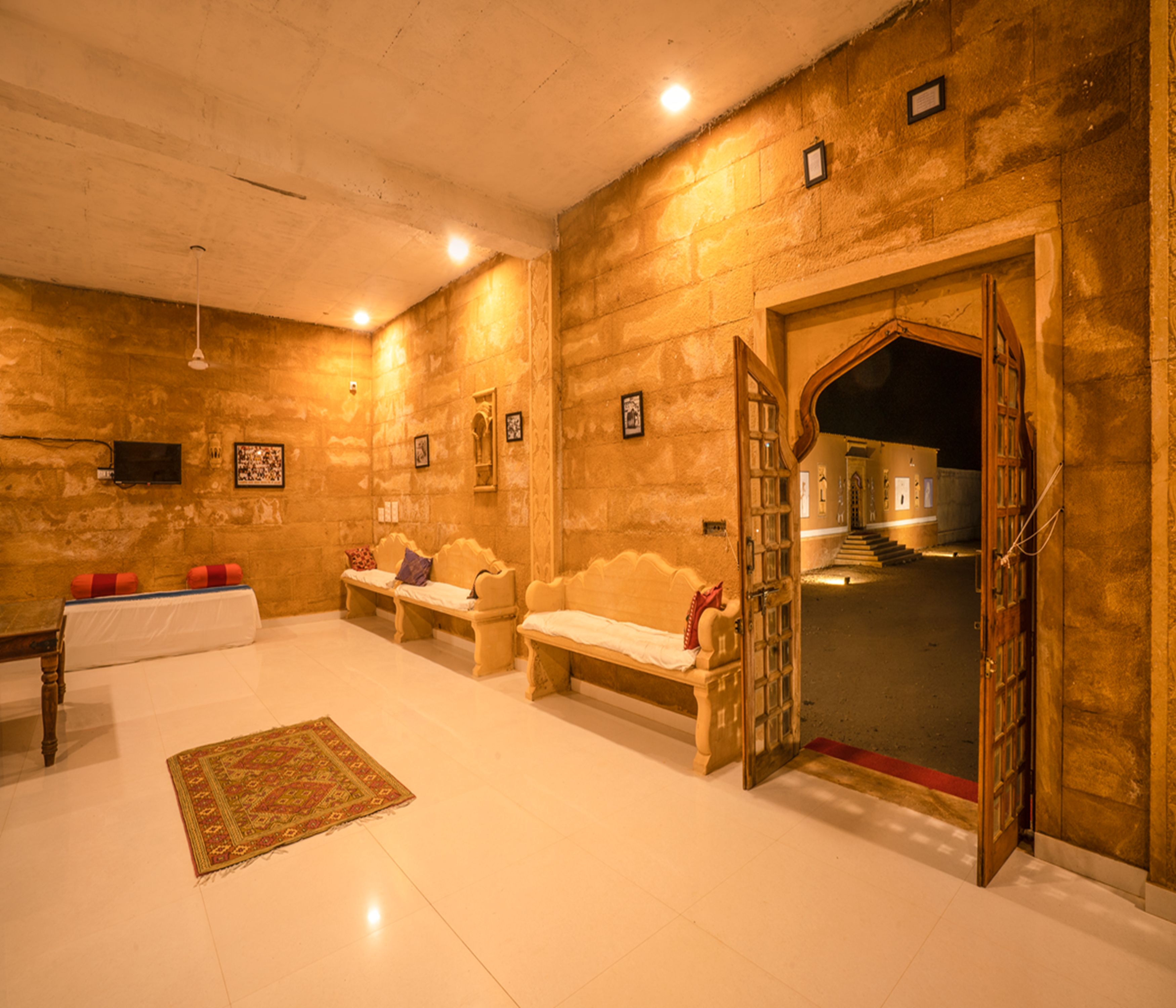 A room with a traditional design, featuring a bench, a sofa, and a patterned rug.