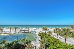 A beach with a tennis court, palm trees, and a clear blue sky. - House Of The Sun #316GF (Sarasota)