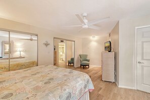 A bedroom with a bed, a ceiling fan, a dresser, a chair, and a television. - House Of The Sun #316GF (Sarasota)