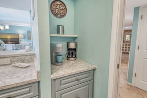 A kitchen with a coffee maker, a kettle, and a coffee cup on the counter. - House Of The Sun #316GF (Sarasota)