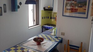 Une petite cuisine avec une table à carreaux, un bol de nourriture et une fenêtre.