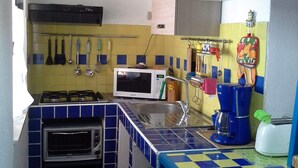 Une cuisine de taille réduite équipée d’un four à micro-ondes, d’une cuisinière et d’un évier.