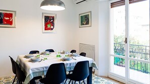 Un'area pranzo con un tavolo apparecchiato per quattro persone, sedie, una lampada a sospensione e opere d'arte alle pareti.