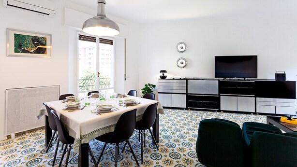 Una cucina moderna con zona pranzo, caratterizzata da un'ampia finestra, una lampada a sospensione e un televisore a schermo piatto.