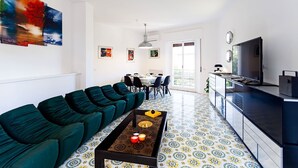 Un soggiorno moderno con divano, tavolino e televisione. C'è anche un'area pranzo con sedie e tavolo.