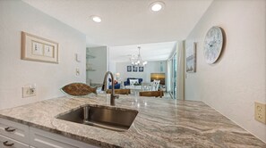 A kitchen with a sink, a fish-shaped mirror, and a dining area with a chandelier. - House Of The Sun #303GS (Sarasota)