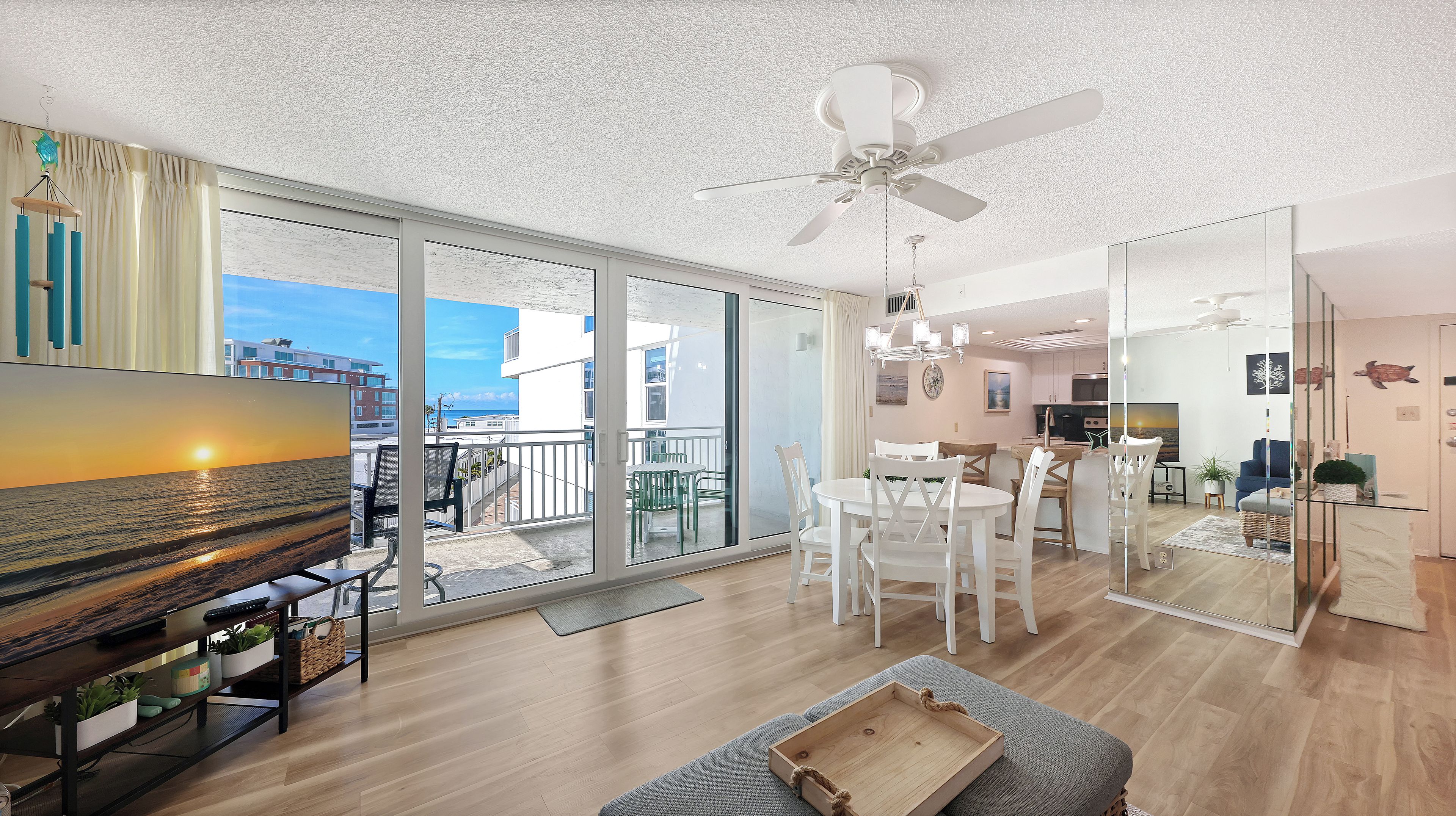 A modern living room with a large TV, a dining area, and a kitchen.