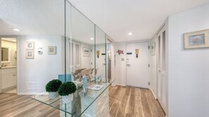 A modern hallway with glass partitions, a wooden floor, and a door with a plaque.