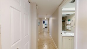A hallway leading to a bathroom with a sink and a mirror. - House Of The Sun #312GV (Sarasota)