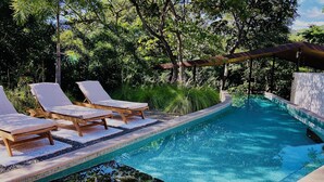 A swimming pool with lounge chairs and a pergola. - Villas Kalei (Cabo Velas)