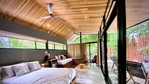 A modern bedroom with a large bed, a desk, and a seating area by a large window. - Villas Kalei (Cabo Velas)