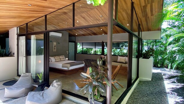 A modern house with a wooden ceiling, glass walls, and a seating area with bean bags. - Villas Kalei (Cabo Velas)