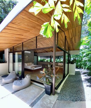 Ein modernes Haus mit Holzboden, Glaswänden und einer Sitzecke mit Sitzsäcken.