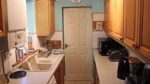 Una cocina compacta con armarios de madera, una puerta blanca y un reloj en la pared.