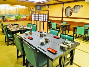 Un restaurante con varias mesas y sillas, cada conjunto con cuencos, palillos y tazas.