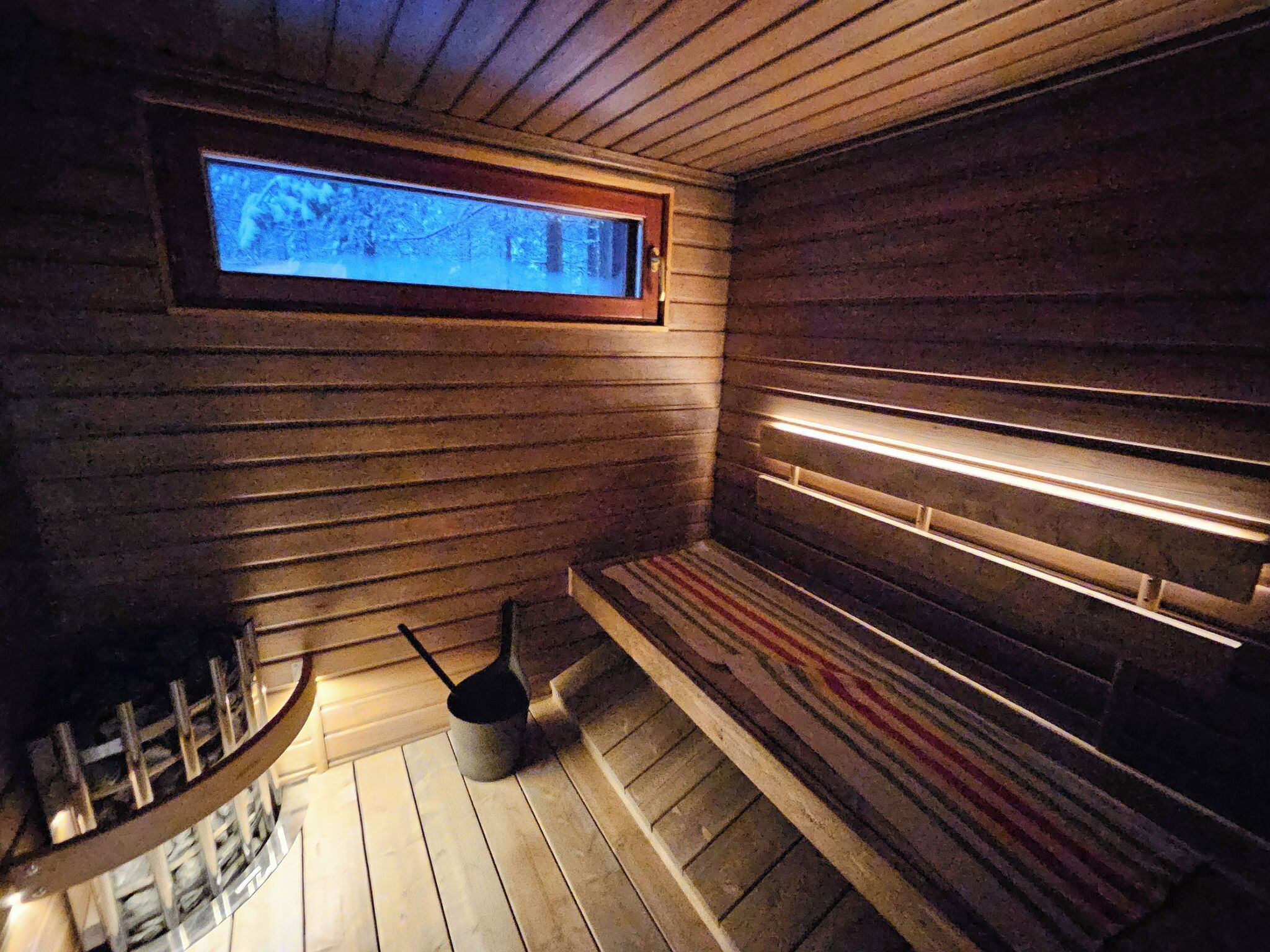 Un sauna avec des murs en bois, un banc et une fenêtre.