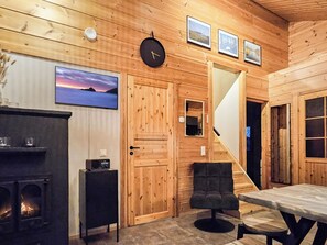 A cozy wooden cabin interior with a fireplace, a clock, and framed pictures on the wall.
