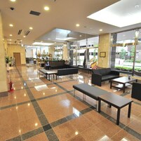 A spacious lobby with a checkered floor, seating areas, and large windows offering a view of the outdoors.