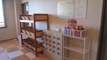 A hotel room with a bunk bed, a minibar, and a bulletin board with notices.