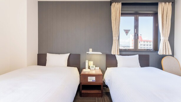 A hotel room with two beds, a nightstand with a lamp, and a window with curtains. - Noshiro Town Hotel Minami (Noshiro)