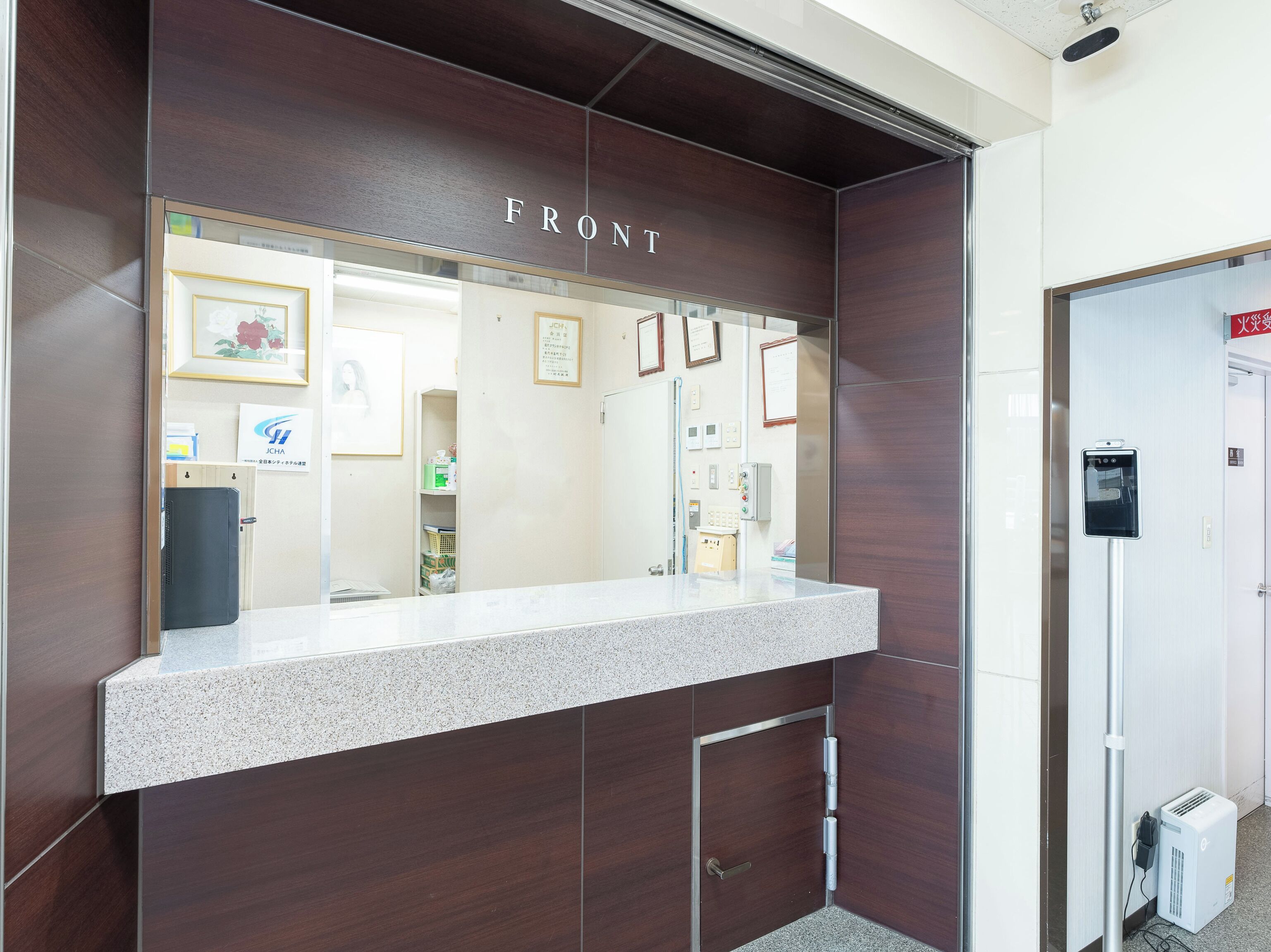 A reception desk with a 'FRONT' sign, a counter, a door, and a small air conditioning unit.