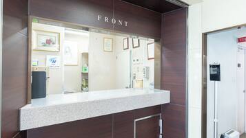 A reception desk with a 'FRONT' sign, a counter, a door, and a small air conditioning unit.