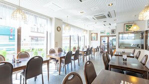 A spacious restaurant with multiple tables and chairs, large windows, and hanging pendant lights. - Noshiro Town Hotel Minami (Noshiro)