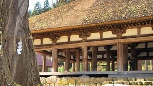 Una construcción tradicional de madera con base de piedra, rodeada de hojas amarillas en el suelo.