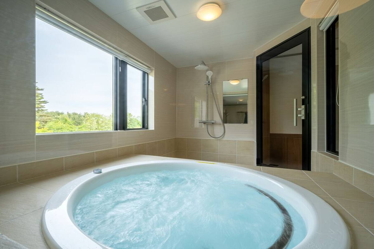 A modern bathroom with a large bathtub, a shower, and a glass door leading to a shower area.