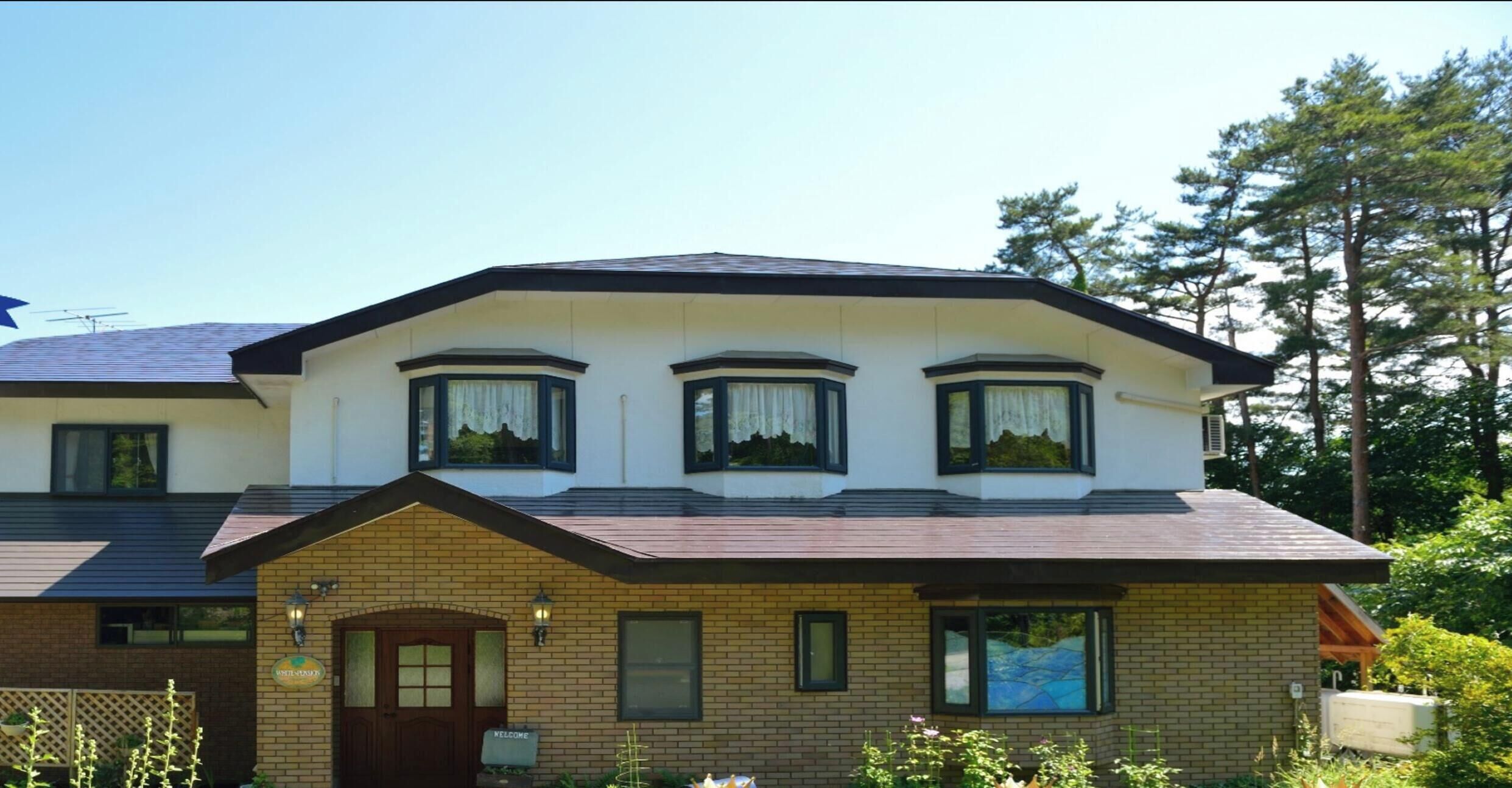 A two-story building with a brick facade, multiple windows with dark frames, and a welcoming sign.