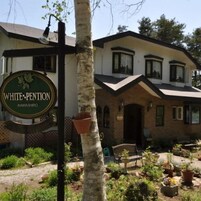 Un edificio con un letrero que dice 'WHITE-PENTION INAVASHIRO' y un jardín con plantas en macetas y un banco.