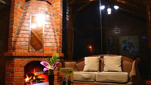 A cozy room with a brick fireplace, a wooden sofa, and a vase with flowers. - Kalera Lodge - Equator Face (Cotacachi)