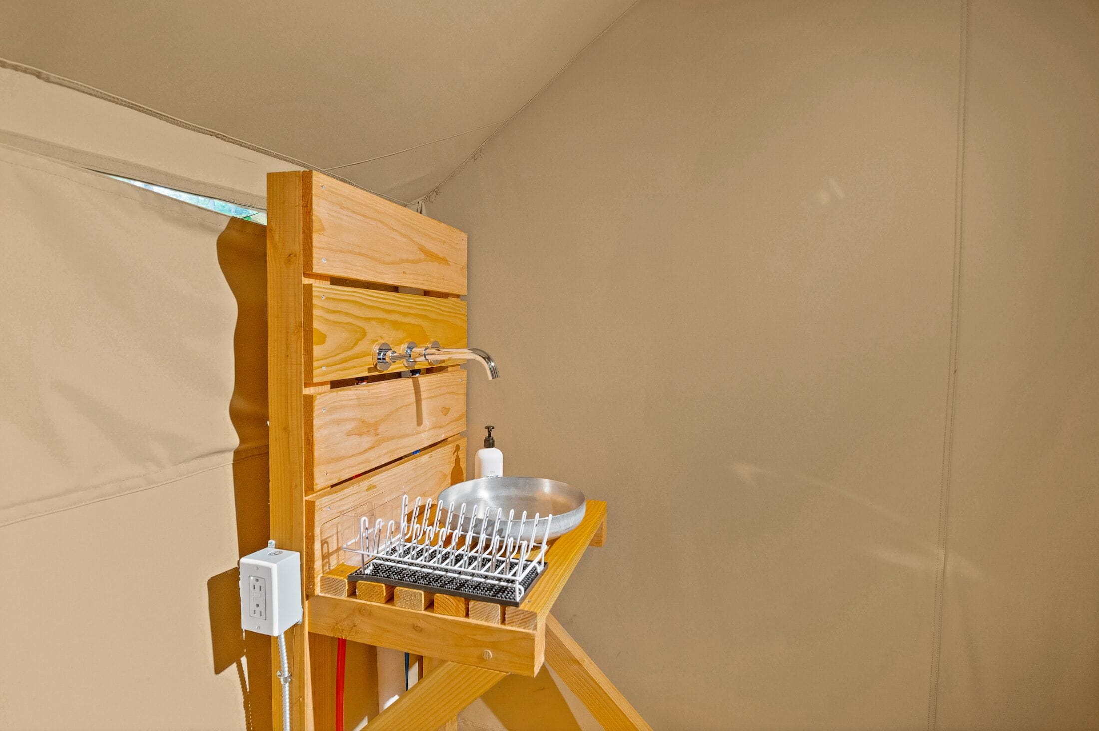 A compact wooden bathroom with a built-in sink and a drying rack.