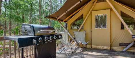 Ein Zelt mit Grill und Stühlen davor.
