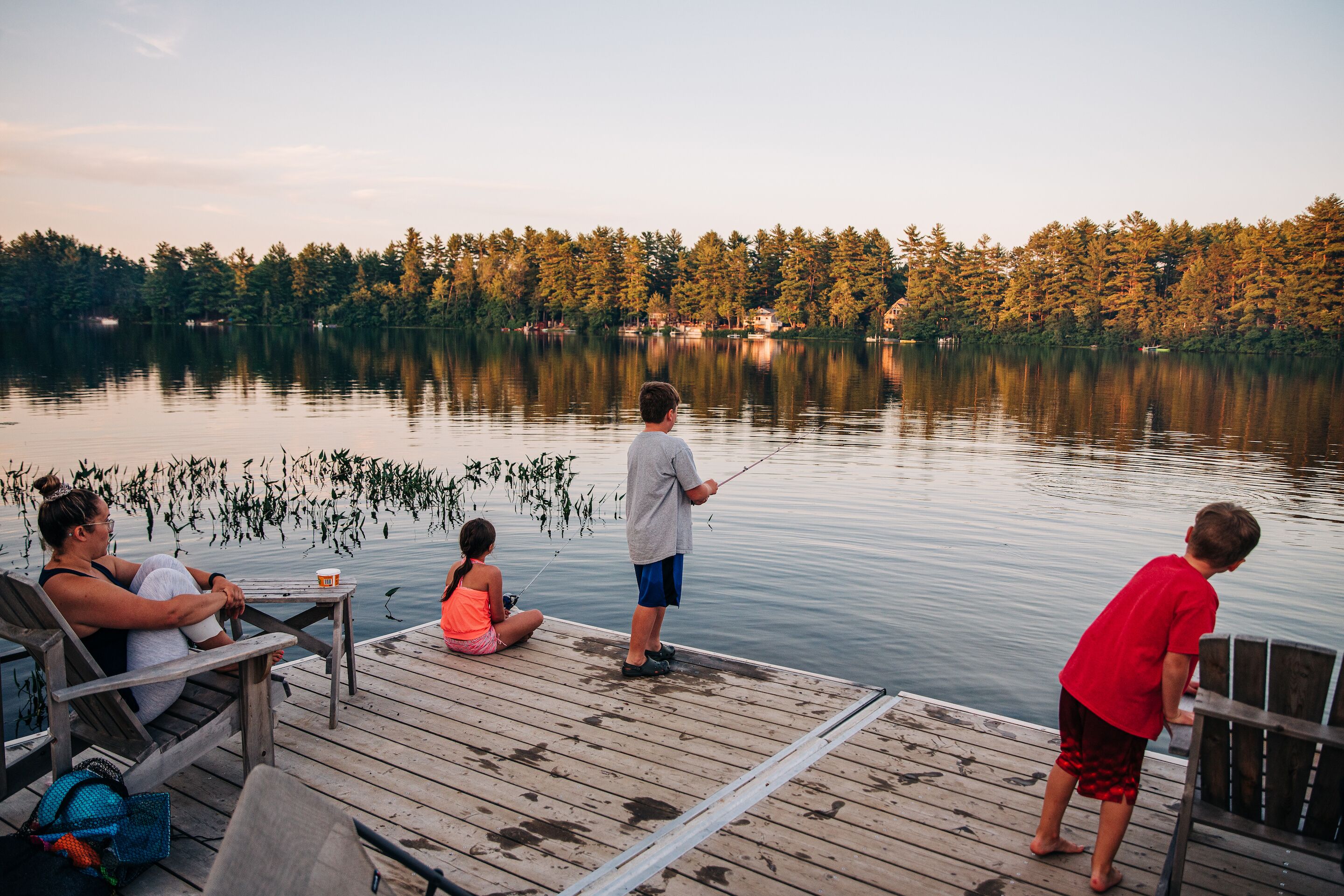 A wooden dock extending into a calm lake with a forested shoreline in the background.