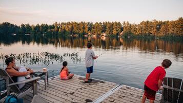 A wooden dock extending into a calm lake with a forested shoreline in the background.