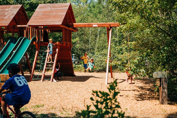A playground with wooden structures, slides, and a swing set.