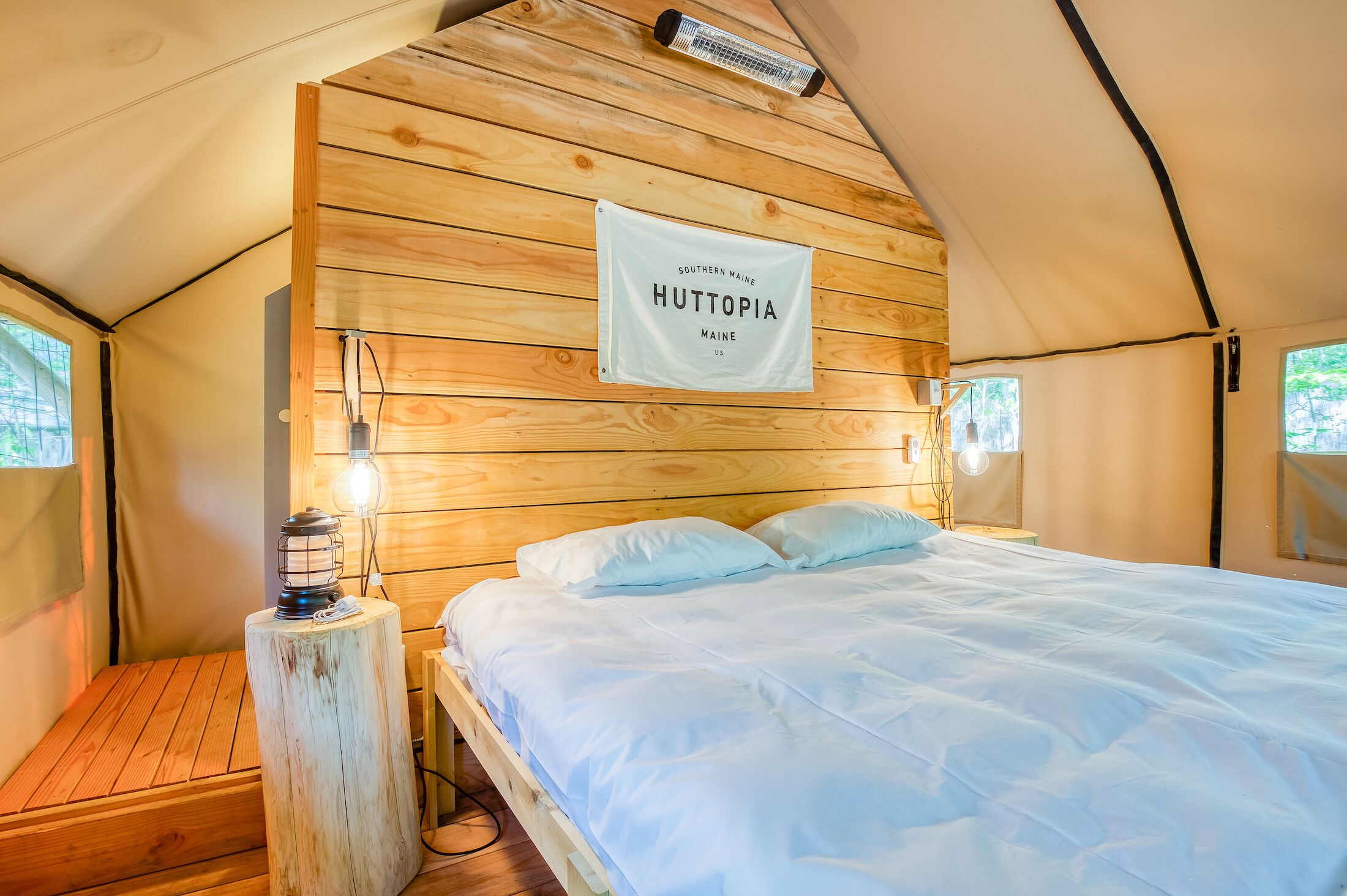 Una habitación tipo tienda de campaña acogedora con cama, paredes de madera, un letrero que dice 