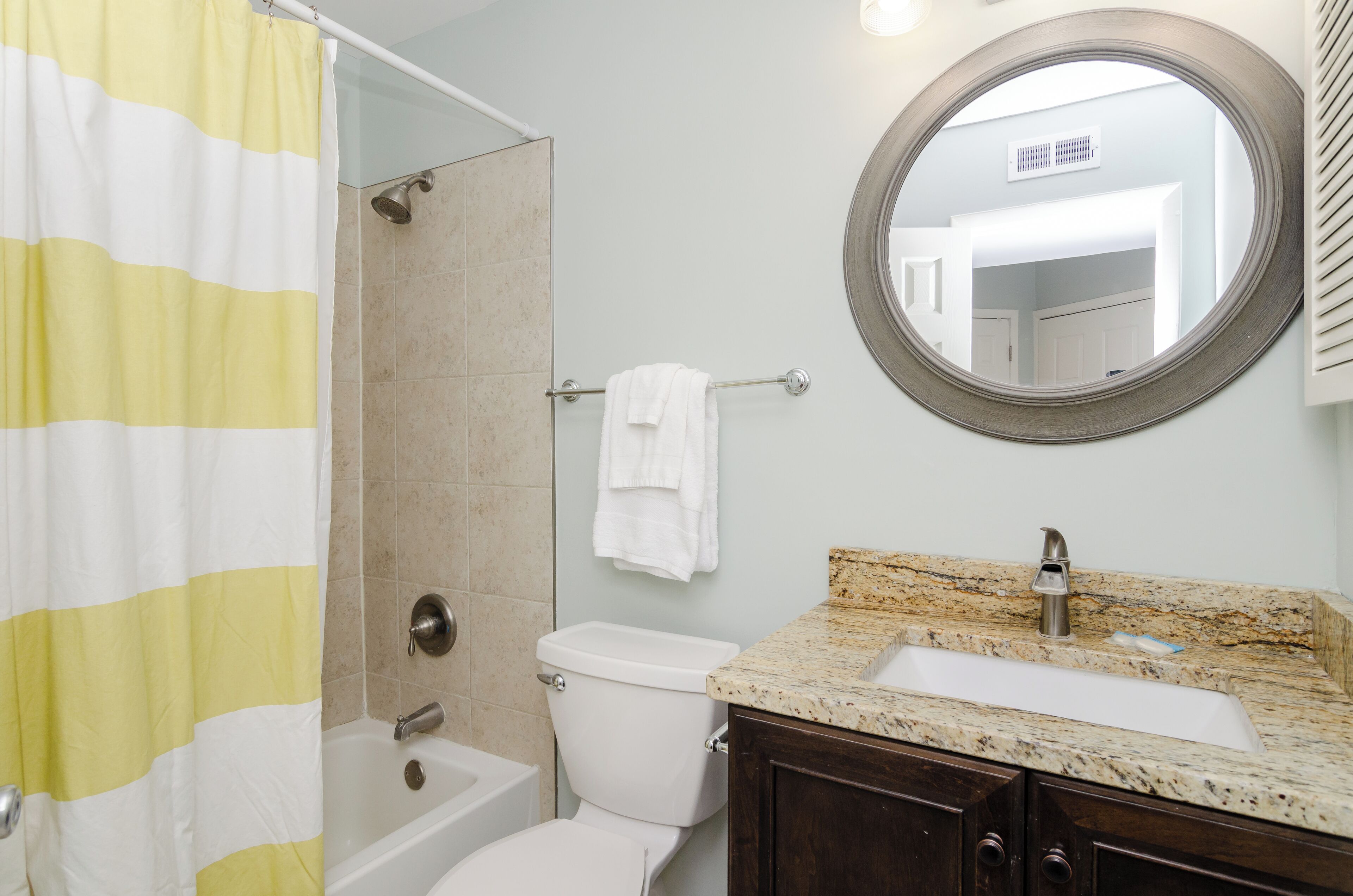 A bathroom with a shower, toilet, sink, and a mirror.