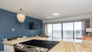 Una cocina moderna con una isla grande, un televisor de pantalla plana y un balcón con vistas.