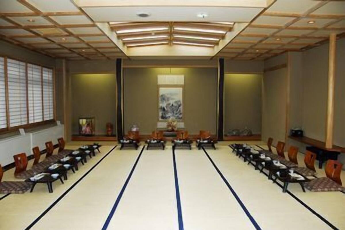 Una sala de conferencias con esteras de tatami, sillas de madera y un techo al estilo japonés tradicional.