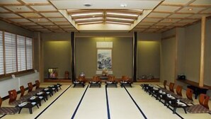 A conference room with tatami mats, wooden chairs, and a traditional Japanese-style ceiling. - Togurakamiyamada Onsen Sanpu So (Chikuma)