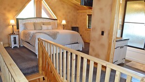 Un dormitorio con cama de madera, dos lámparas de noche, una ventana con persianas y vistas al exterior.