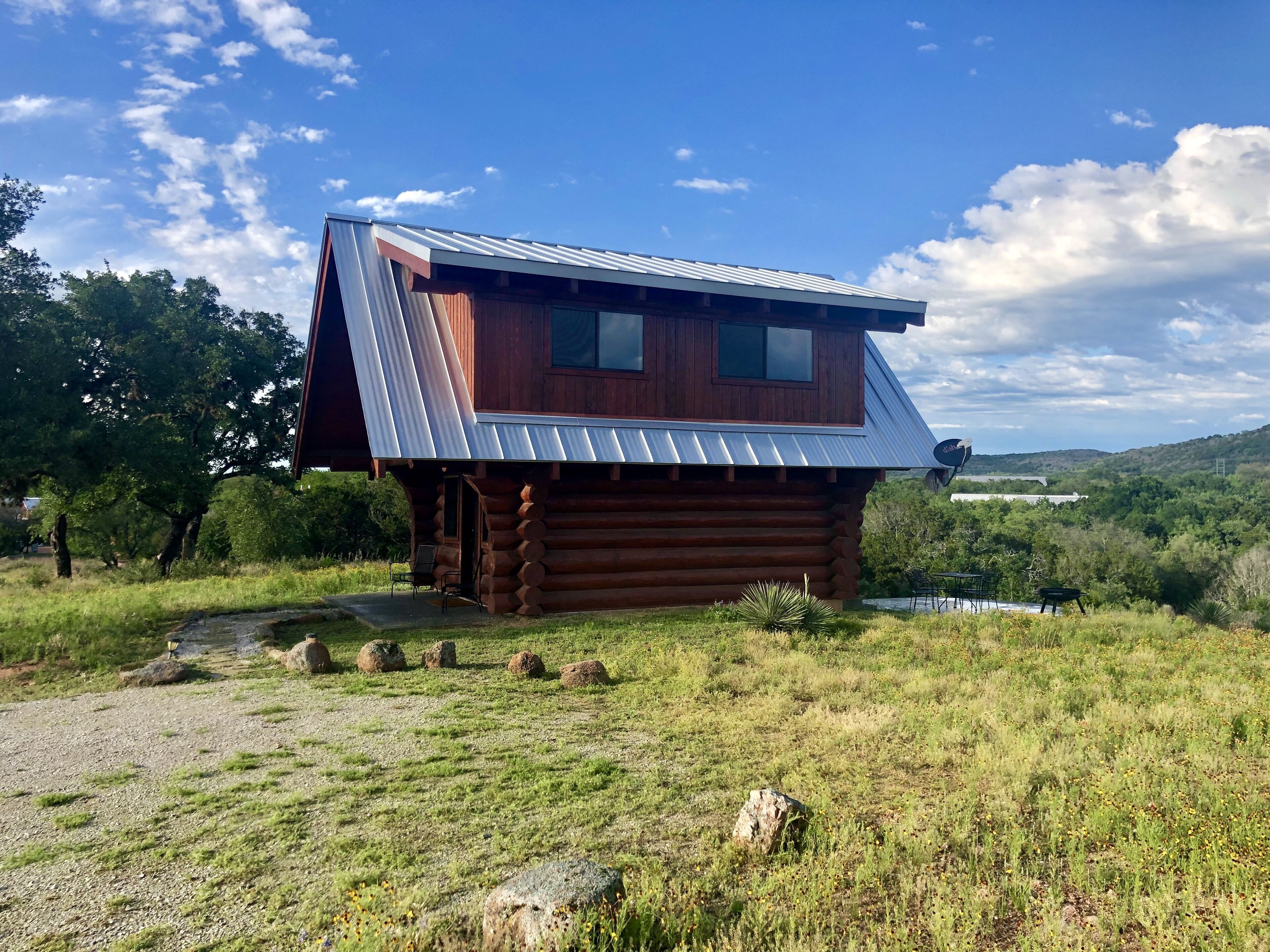 A log cabin with a sloped metal roof, a small porch, and a view of a valley.
