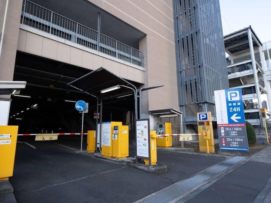 A parking garage entrance with a 24-hour sign, yellow barriers, and directional signs.
