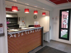 A reception desk with a clock, a bulletin board, and a window with a snowman decoration. - Résidence VALORIA (Blois)